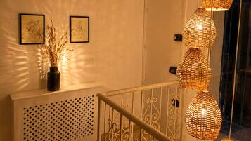 Una escalera con barandilla blanca, una pared con dos cuadros enmarcados y una puerta.