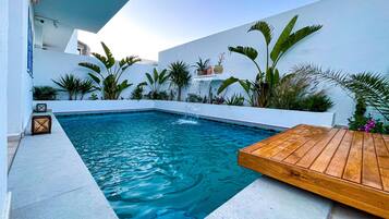 Una piscina al aire libre, sillones reclinables de piscina