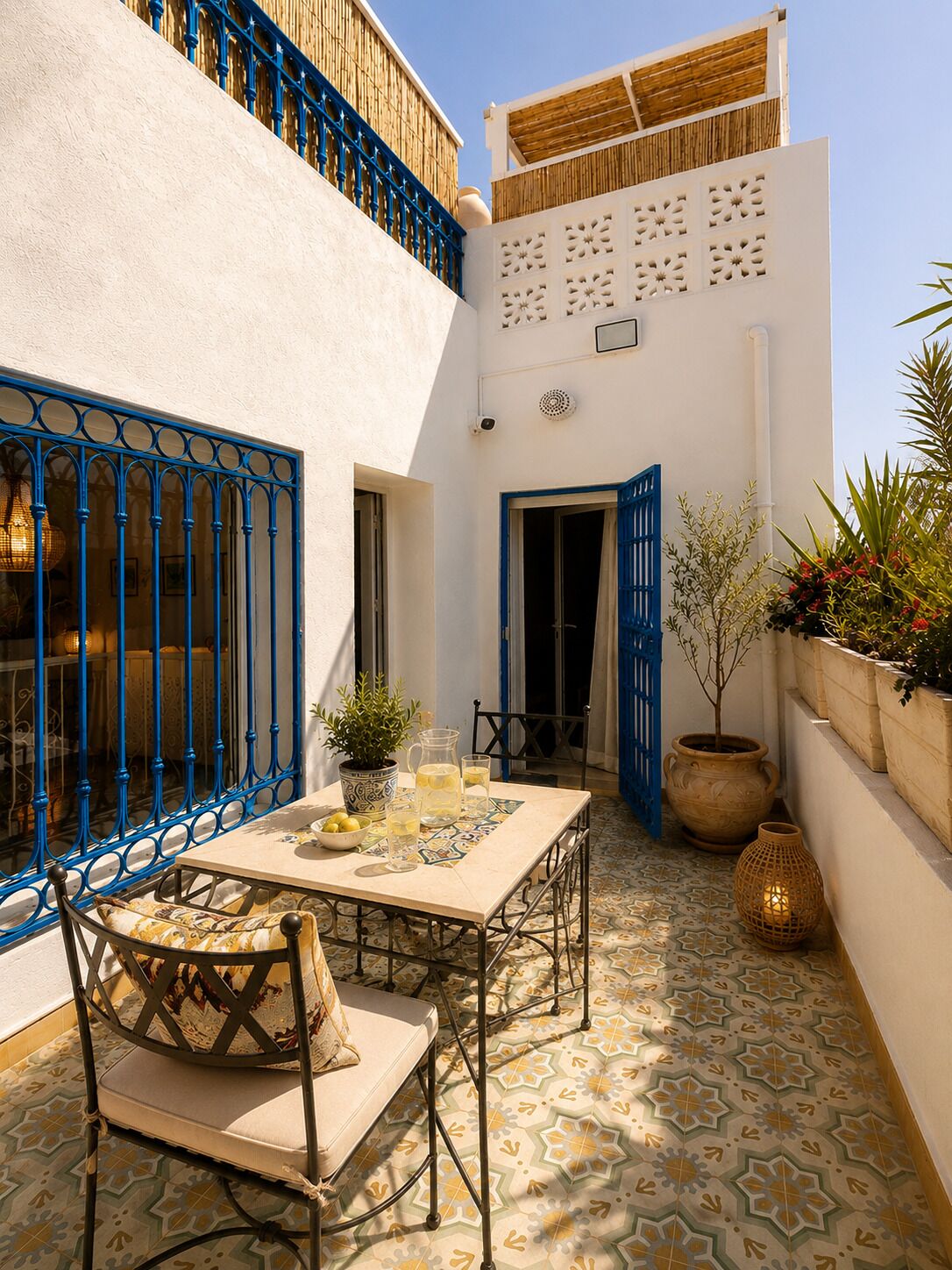 A courtyard with a table and chairs, a potted plant, and a door.