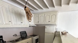 Una cocina con gabinetes blancos, estufa, refrigerador y un colgador para ollas.