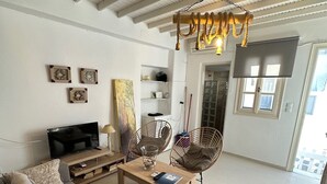 Una sala de estar con un sofá, una mesa de centro, sillas, un televisor y un ventilador de techo.