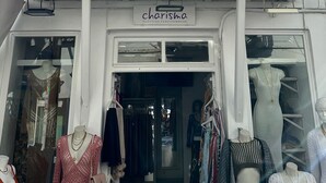 Un edificio blanco con un balcón y un letrero que dice 'charisma CLOTHING FASHION & MORE'.