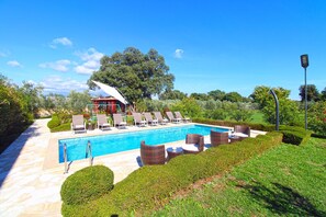 Una piscina con sillones de descanso y un pabellón.