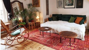 Una habitación acogedora con cama, una mecedora, una mesita y varias decoraciones en las paredes, incluyendo un cráneo y cuadros enmarcados.