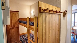 Et værelse med køjesenge, et træskab og et lille bord med stole.