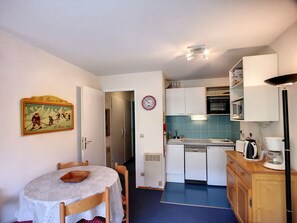 A compact kitchen with a dining area, featuring a small table, chairs, and basic appliances.