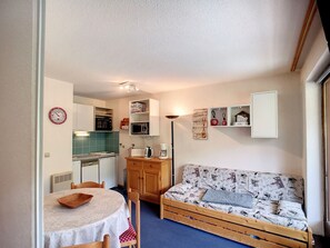 A compact living space with a kitchenette, a dining area, and a sofa.