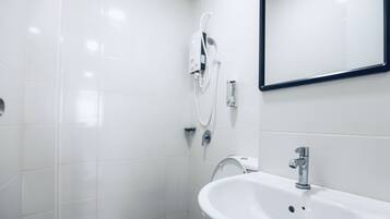 Un baño moderno con baldosas blancas, un lavabo, un espejo y una ducha.