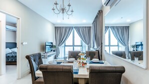 Een moderne hotelkamer met een zithoek, inclusief een tafel gedekt voor twee personen, een televisie en een potplant.