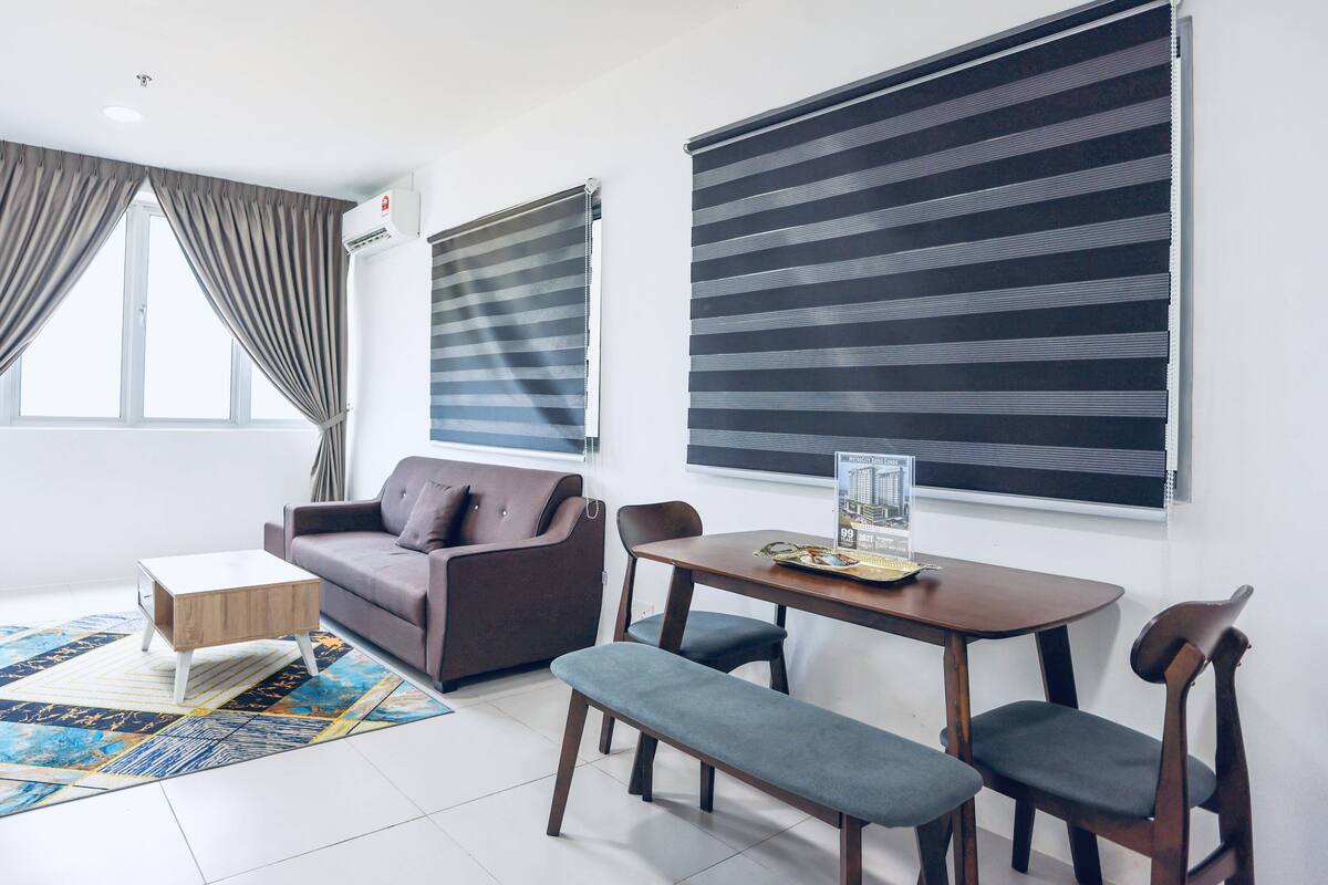 Una sala de estar moderna con un sofá, una mesa de centro, una mesa de comedor con sillas y un ventanal con cortinas.