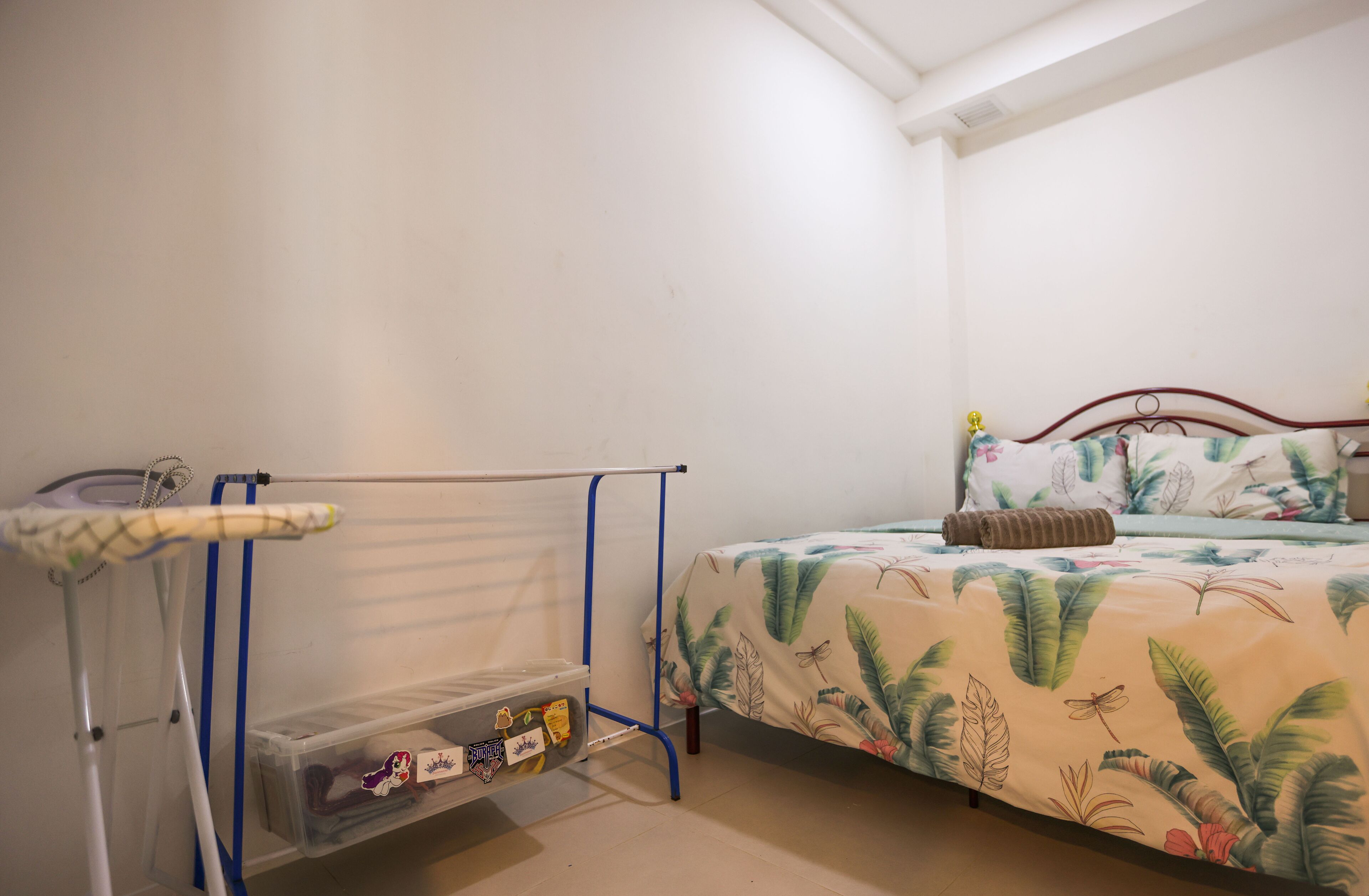 A bedroom with a bed, a drying rack, and a storage unit.