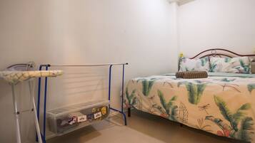 A bedroom with a bed, a drying rack, and a storage unit.