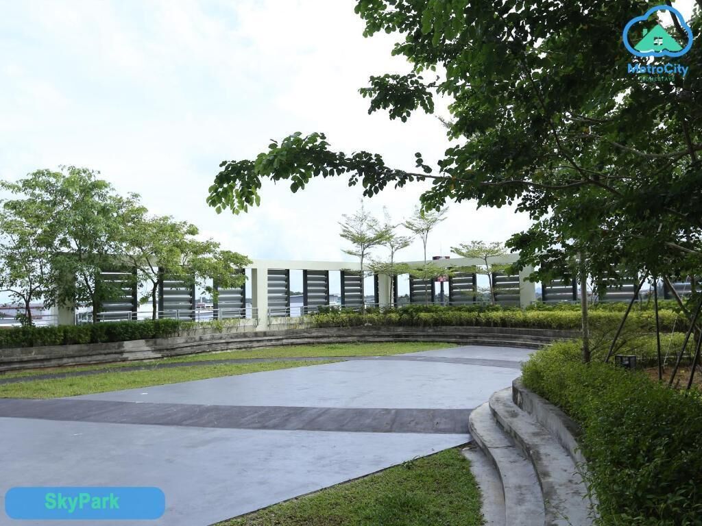 A landscaped area with a curved pathway, trees, and a building with a modern design.