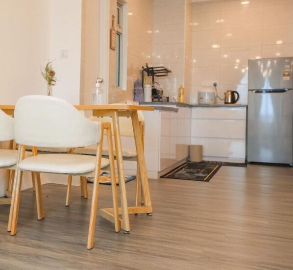 Une cuisine moderne avec des chaises en bois, un réfrigérateur en acier inoxydable et des armoires blanches.