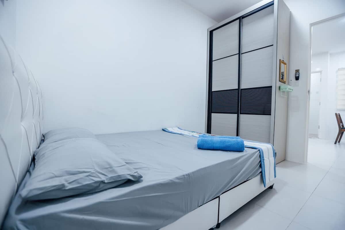 Un dormitorio moderno con una cama individual, un armario con puerta corredera y una pequeña mesa en la esquina.