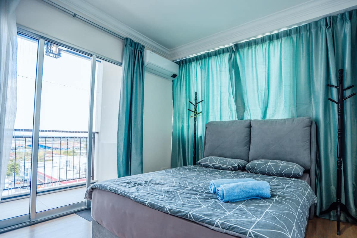 Un dormitorio con una cama grande, cortinas color turquesa y vistas al exterior.