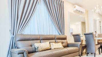Uma sala de estar moderna com um sofá de couro, uma área de jantar com mesa e cadeiras, e uma janela grande com cortinas.