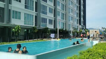 A swimming pool surrounded by lush greenery, with a modern building in the background.