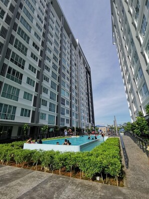Edifici residencial modern amb una piscina envoltada de verdura.