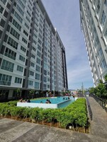 Un moderno edificio residencial con piscina rodeada de vegetación.
