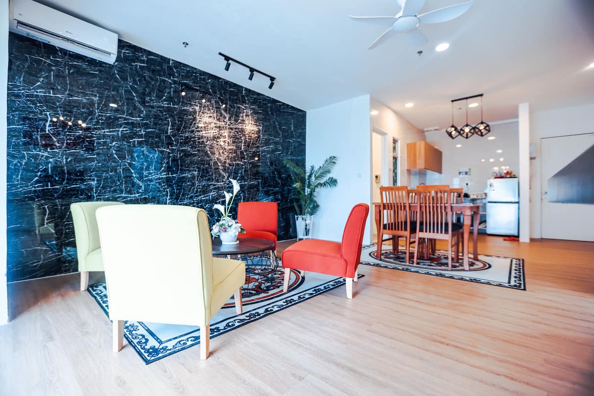 Una sala de estar moderna con una pared de mármol negro, un comedor con mesa y sillas de madera, y una cocina al fondo.