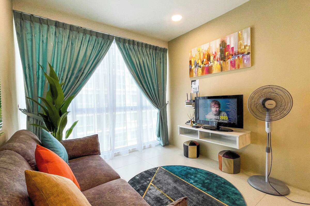 Una sala de estar con sofá, televisor y un ventilador de pie.
