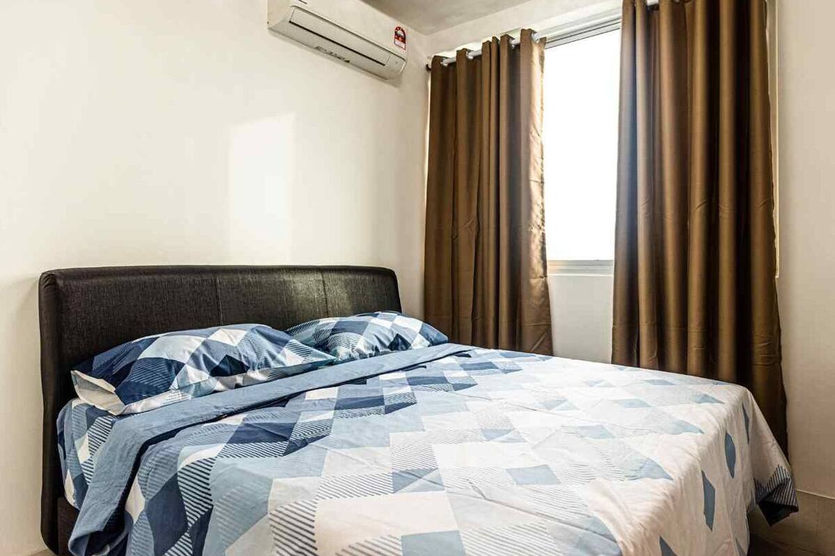 Un dormitorio con cama, ventana con cortinas, equipo de aire acondicionado y detector de incendios en la pared.