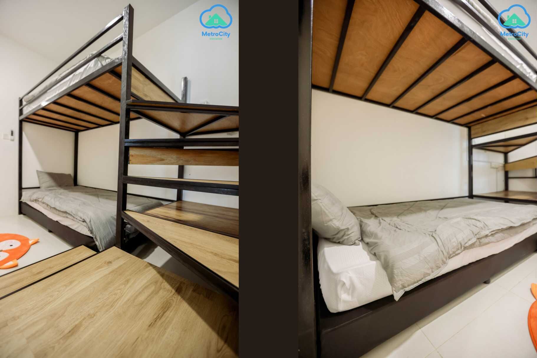 Une chambre avec un lit superposé, un plancher en bois, un mur blanc et une fenêtre.