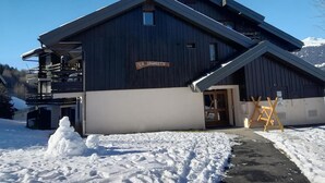A chalet named "LA GRANGETTE" with a wooden exterior, a balcony, and a snow-covered ground.