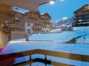 A ski resort with wooden buildings, a snow-covered slope, and a person skiing. - Renovated apartment for 5, near slopes and shops, south balcony, parking included (La Plagne Montalbert)