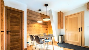 Una cocina moderna con paredes de madera, una mesa de comedor con sillas, luces colgantes y un cubo de basura.