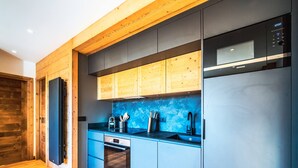 Una cocina moderna con armarios de madera, encimera azul y refrigerador de acero inoxidable.