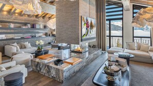 A modern living room with a fireplace, comfortable seating, and a large window with a mountain view.