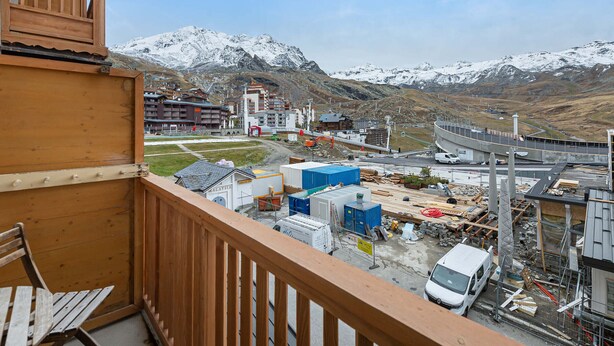 Ein Balkon mit Blick auf eine Baustelle und eine Bergkulisse.