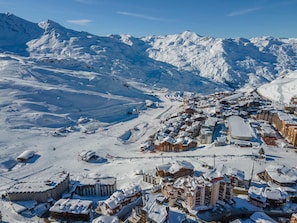 A snow-covered mountain town with ski slopes, buildings, and a clear sky.
