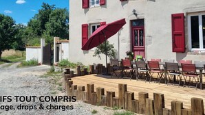 A building with red shutters and a wooden deck with chairs and tables. - Spacious lodging with pool and pets allowed for 15 guests (Mornand-en-Forez)