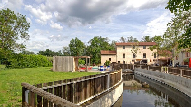 A riverside area with a wooden walkway, a small wooden structure, and a building with a red roof. - Spacious lodging with pool and pets allowed for 15 guests (Mornand-en-Forez)
