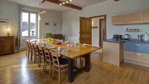A spacious kitchen with wooden cabinets, a dining table with chairs, and a built-in island. - Spacious lodging with pool and pets allowed for 15 guests (Mornand-en-Forez)
