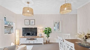 A modern living room with a TV, white furniture, and two hanging light fixtures. - Contemporary Comfy ~ 2Bed/2Bath/1Car ~ Hawthorne (Hawthorne)