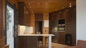 Eine moderne Küche mit Holzausstattung, einer zentralen Kochinsel inklusive Sitzgelegenheiten und integrierten Geräten.