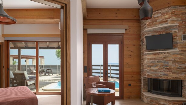 Ein Zimmer mit Kamin, Blick auf den Pool und einer Essecke mit Tisch und Stühlen.