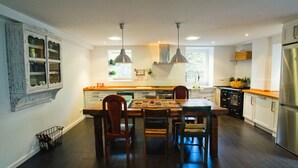 A modern kitchen with a central island, pendant lighting, and a refrigerator. - Casa Boutique en Puerto Pesquero de Asturias (Viavélez)