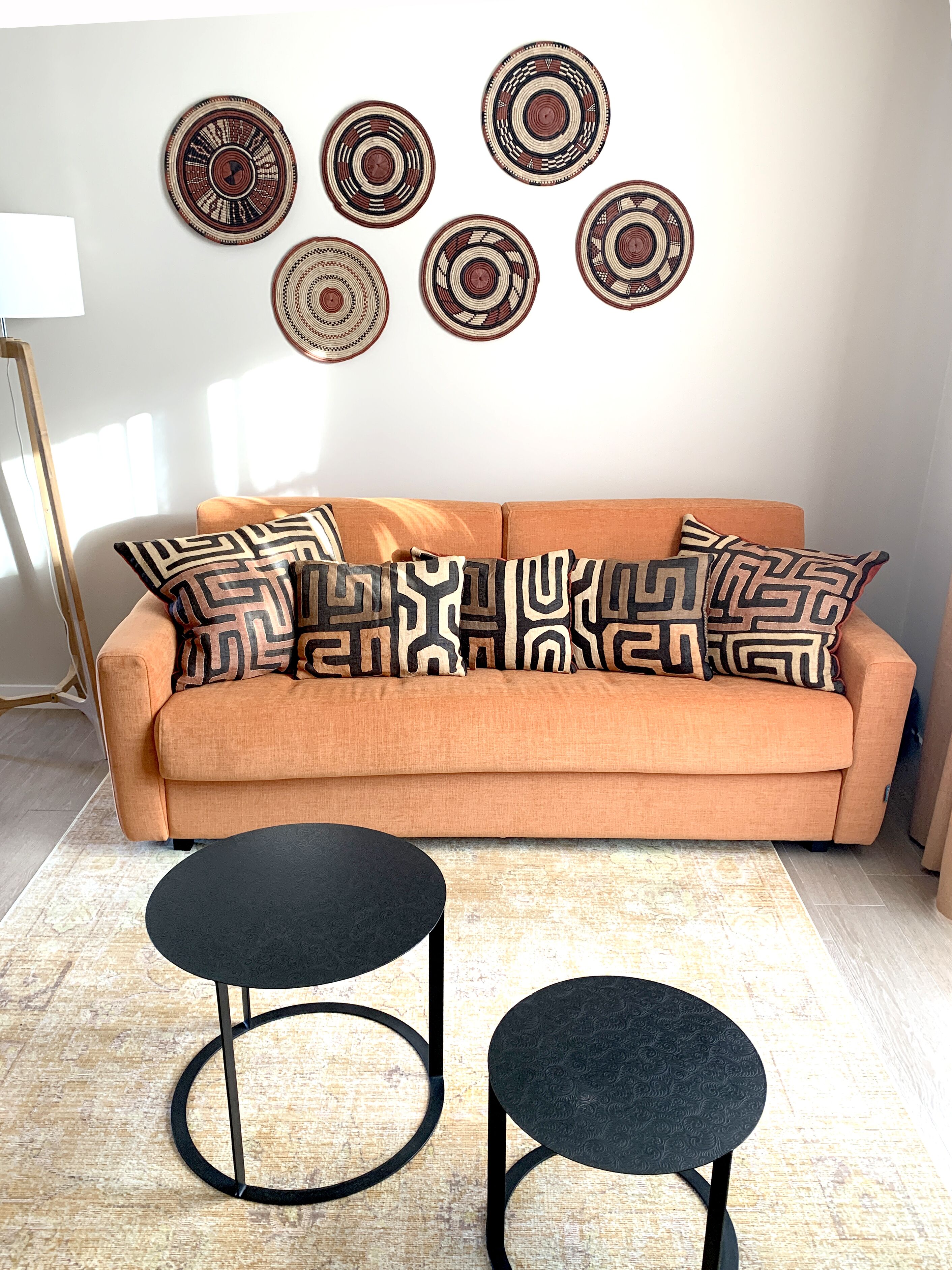 Ein Wohnzimmer mit einem orangefarbenen Sofa, gemusterten Zierkissen und einem schwarzen Couchtisch.