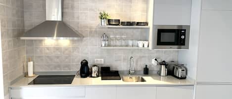 A modern kitchen with a stainless steel range hood, a built-in microwave, and a coffee maker.