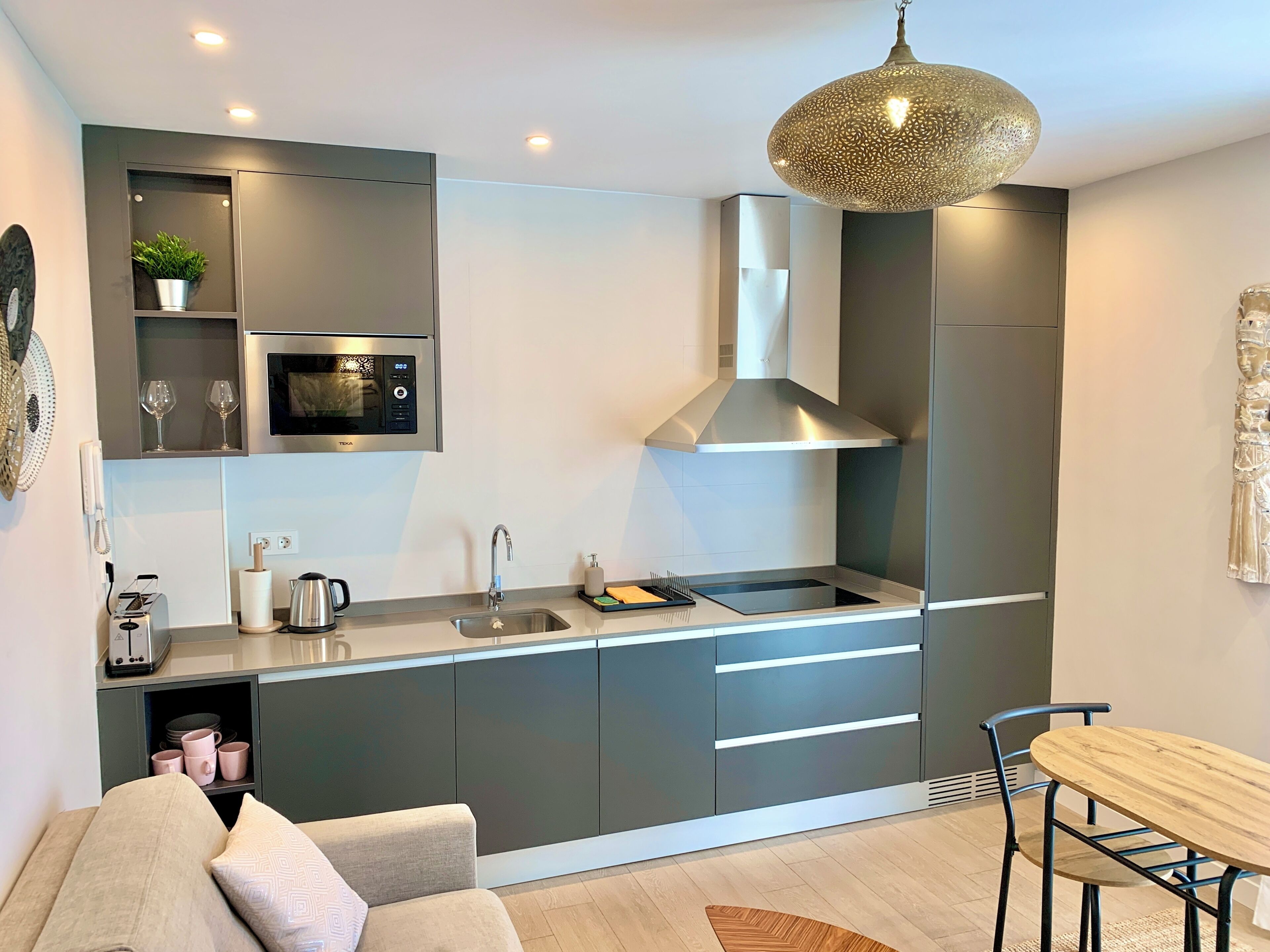 A modern kitchen with a built-in microwave, stainless steel sink, and a large overhead range hood.