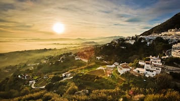 Un pueblo en la ladera con casas blancas tradicionales, campos en terrazas y una vista despejada del paisaje circundante.