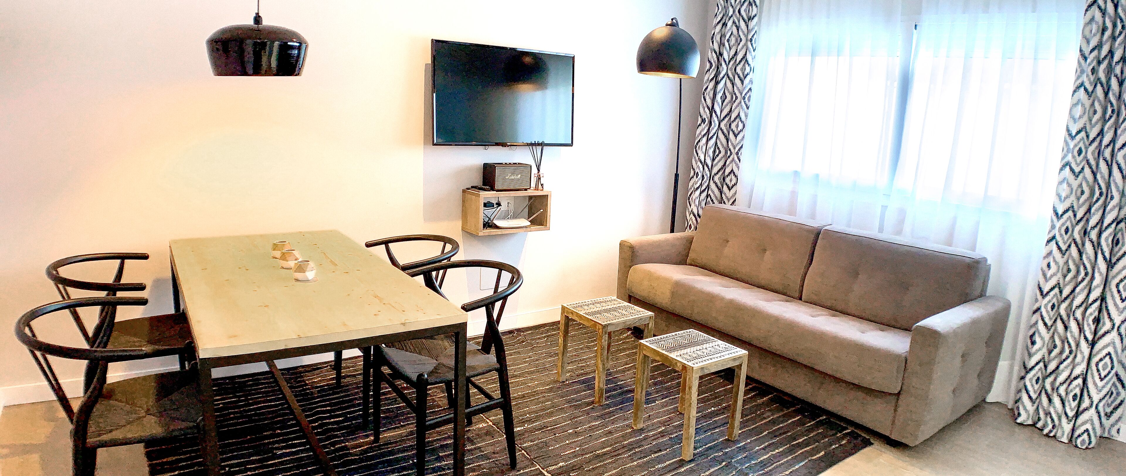 Una sala de estar con un sofá, un televisor, una mesa y dos mesitas auxiliares.