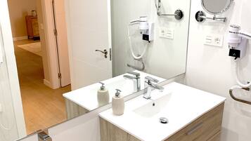 Un baño moderno con tocador doble, un espejo grande y un secador de pelo montado en la pared.