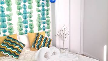 Un dormitorio con una cama, almohadas, una pared con diseño de hojas, una lámpara colgante azul y una puerta.