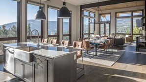 Een ruime keuken met een groot eiland, moderne hanglampen en grote ramen met uitzicht op de bergen.